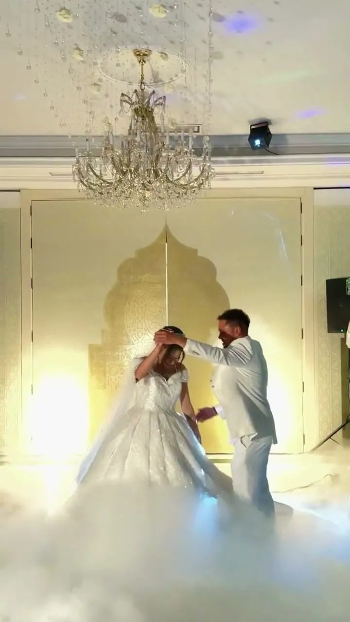 Primer baile de los novios entre humo bajo una lámpara de araña
