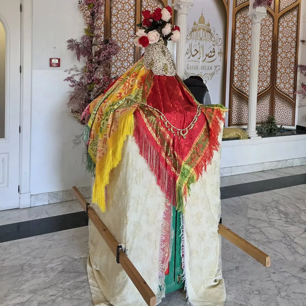 Caftán tradicional marroquí con mantón rojo y arco de flores