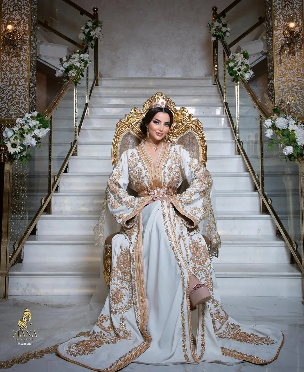 Novia en trono dorado al pie de la escalinata, caftán blanco y oro