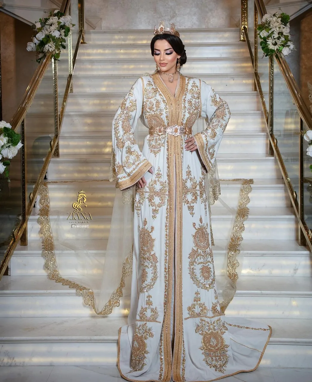 Novia de pie con caftán blanco de bordados dorados y velo de tul