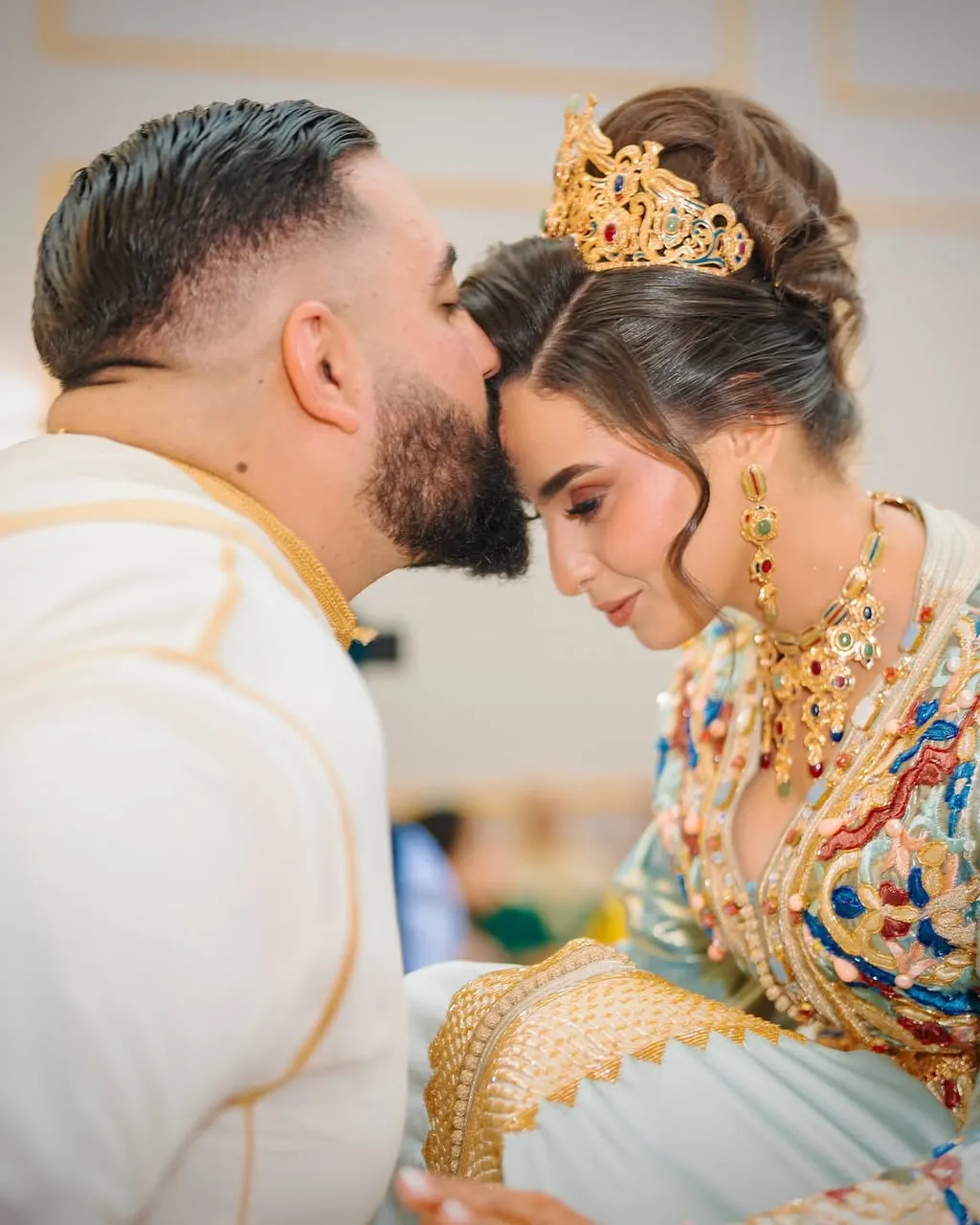 Novio besando la frente de la novia, ambos con corona dorada