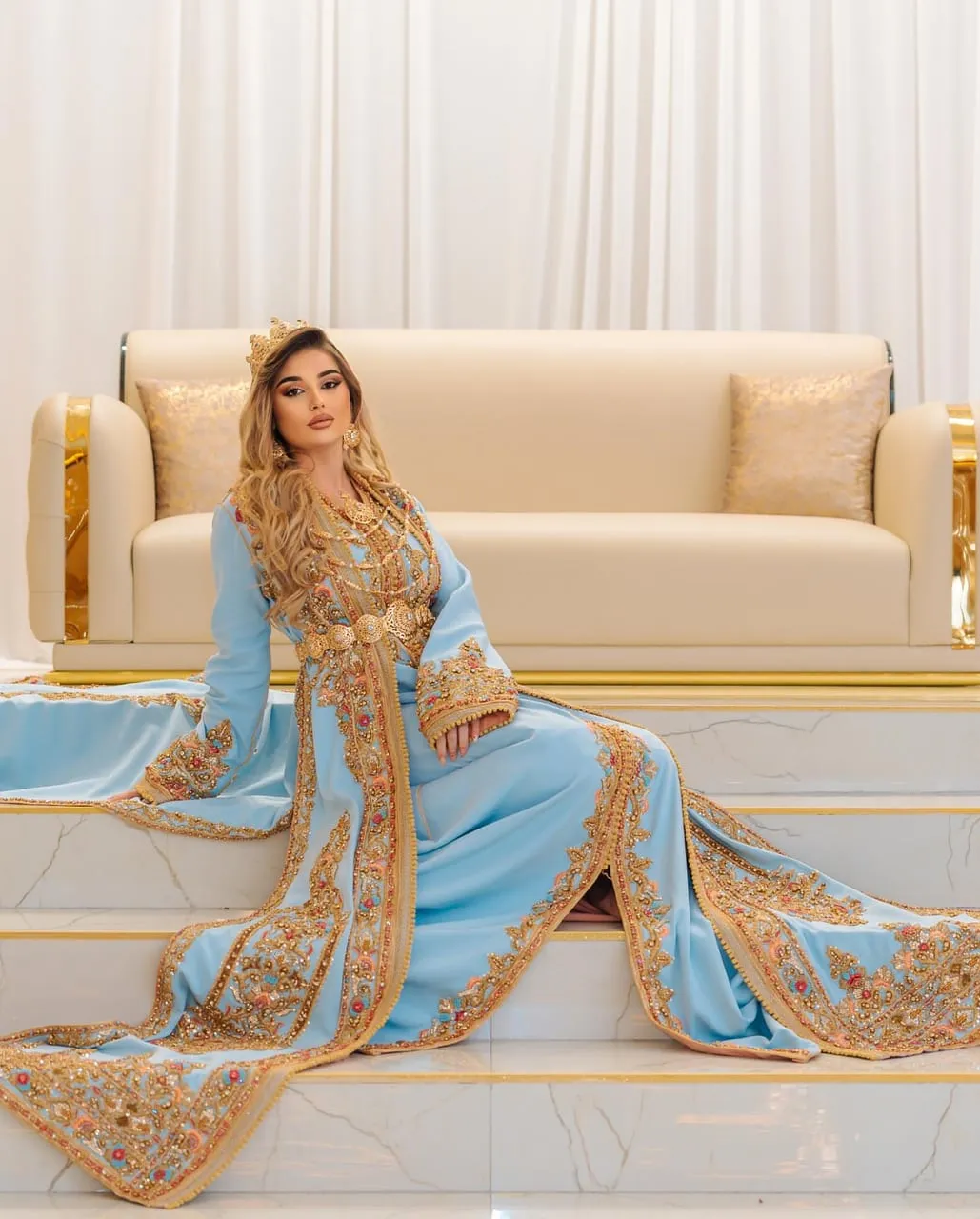Novia con takchita azul celeste y cinturón dorado en una escalinata
